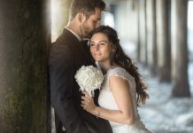 Two lovers embrace by the pier ocean with tuxedo and wedding dre