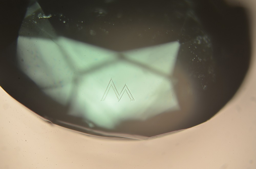 Myne London 'M' monogram placed beneath the surface of the crown using the Opsydia Sub-Surface System D5000, photographed at 100x magnification.